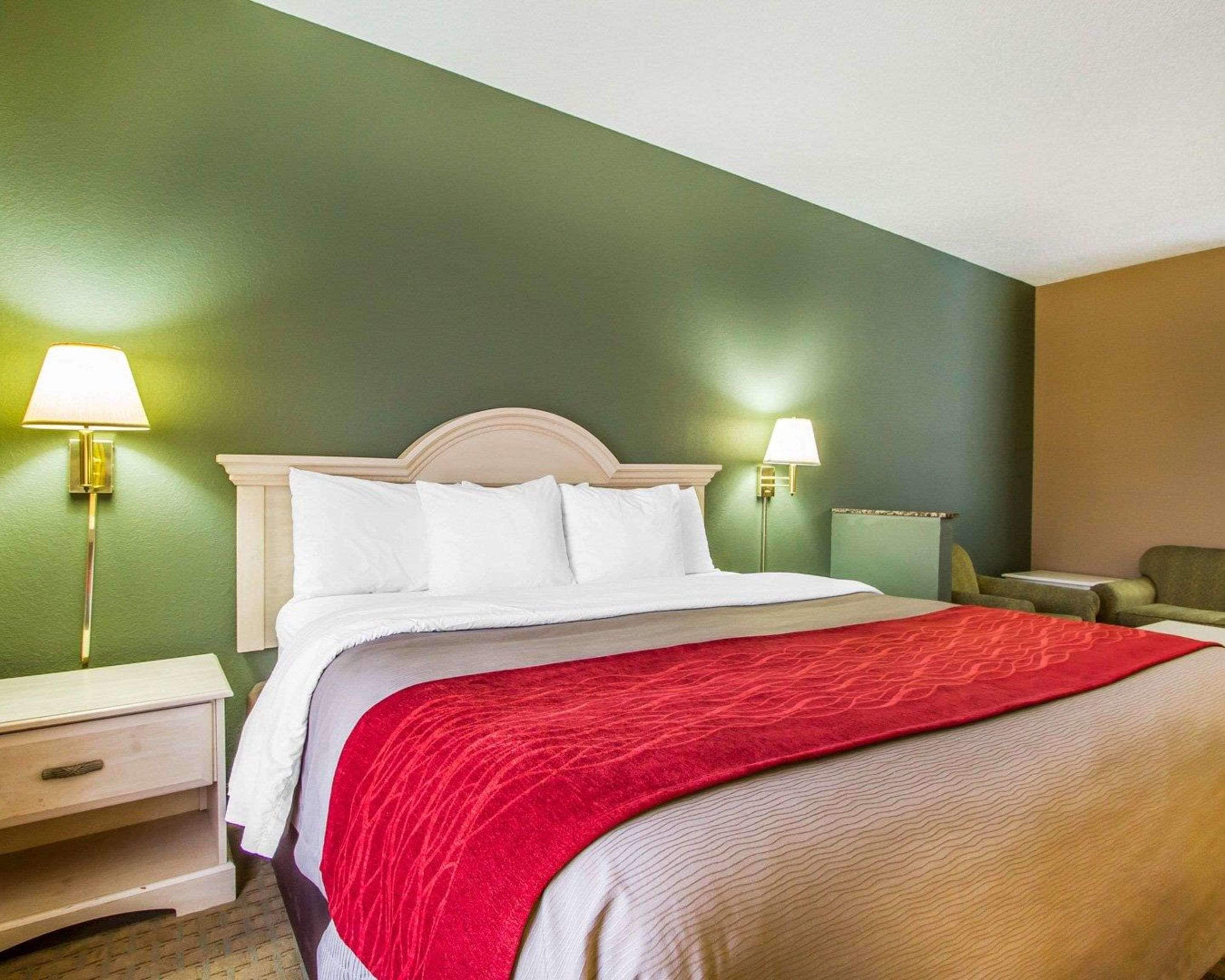 Une chambre d’hôtel comprenant un lit, deux tables de chevet et deux lampes fixées au mur.