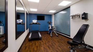 A gym with a treadmill, elliptical, and weight bench.