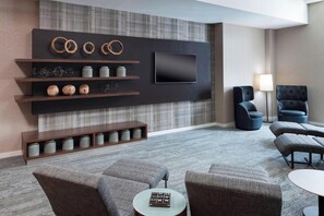 A modern living room with a flat-screen TV, built-in shelves, and seating. - Courtyard by Marriott Omaha Downtown (Omaha)