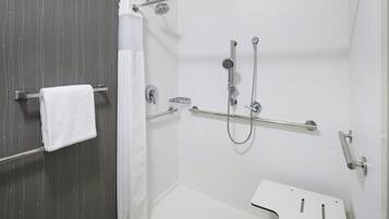 Un espace douche doté d’une cabine de douche en verre, d’un pommeau de douche à main et d’un pommeau de douche à main avec un flexible.