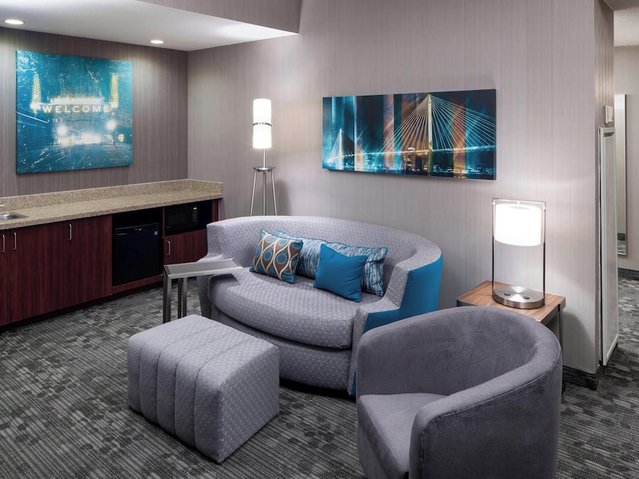 Una habitación de hotel moderna con kitchenette, un sofá, una silla y un escritorio.