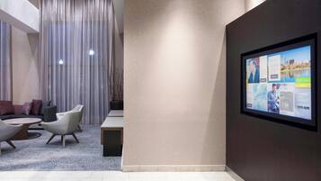 Una hall moderna con angolo salotto, un grande schermo digitale e vista sull'esterno.