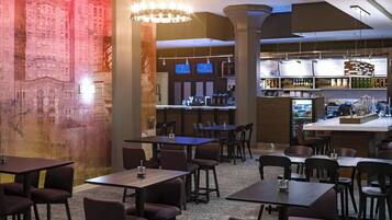 A modern restaurant with a bar area, multiple tables and chairs, and a decorative wall with a mural.