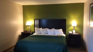 A hotel room with a large bed, two bedside tables, and green walls.