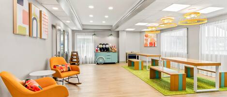 A modern interior with orange rocking chairs, a blue cabinet, and a wooden table with benches.