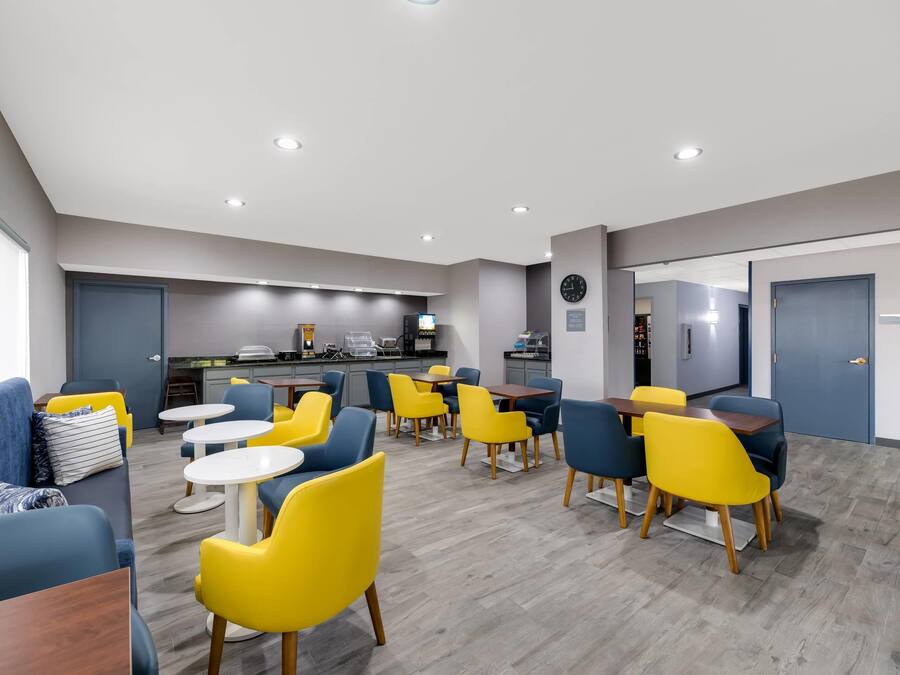 A modern hotel lobby with a dining area, a kitchen, and a reception desk.