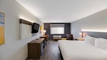 A hotel room with a bed, a desk, a chair, a TV, and a window.