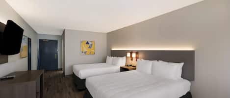 A hotel room with two beds, a desk, a chair, a door, and a wall-mounted TV.