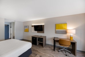 Une chambre d’hôtel équipée d’un lit, d’un bureau, d’une chaise, d’une télévision et d’une lampe.