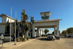 A hotel with a sign reading 'Quality Inn & Suites by Choice Hotels' and a parking lot with vehicles. - Quality Inn & Suites Artesia (Artesia)