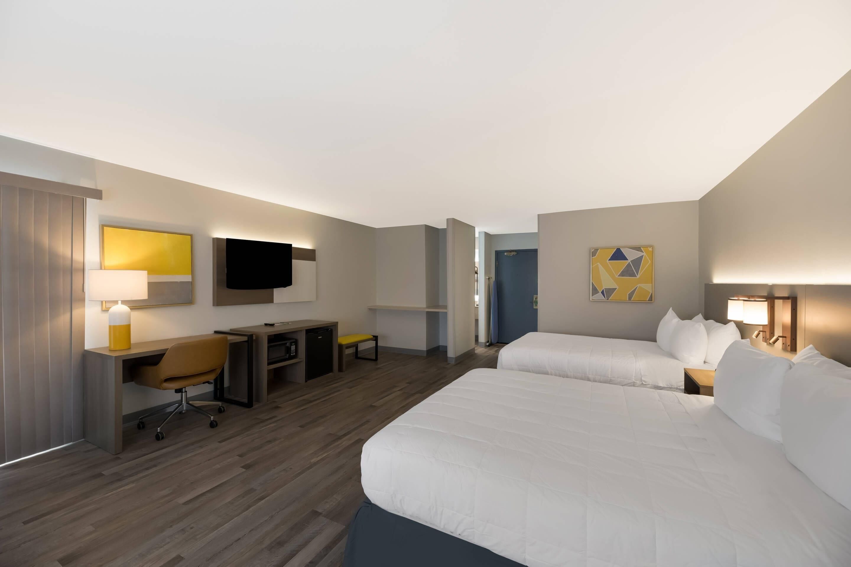 Una habitación de hotel con cama, escritorio, silla y televisor.