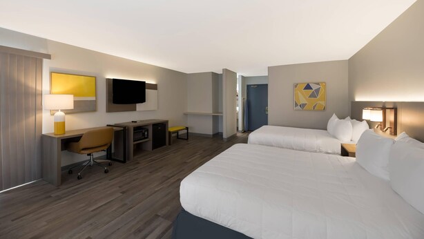 Ein Hotelzimmer mit Bett, Schreibtisch, Stuhl und Fernseher.