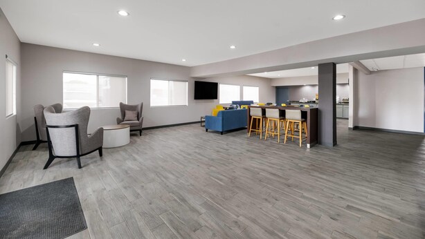 A spacious living area with a kitchen, grey furniture, and a bar area. - Quality Inn & Suites Artesia (Artesia)