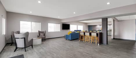 Amplia sala de estar con cocina, muebles grises y una zona de bar.