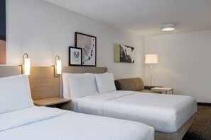Een hotelkamer met twee bedden, een nachtkastje, een lamp en twee kunstwerken aan de muur.
