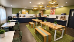 A modern kitchen with wooden tables and benches, green walls, and overhead lighting. - Spark by Hilton Tempe Phoenix Airport (Tempe)
