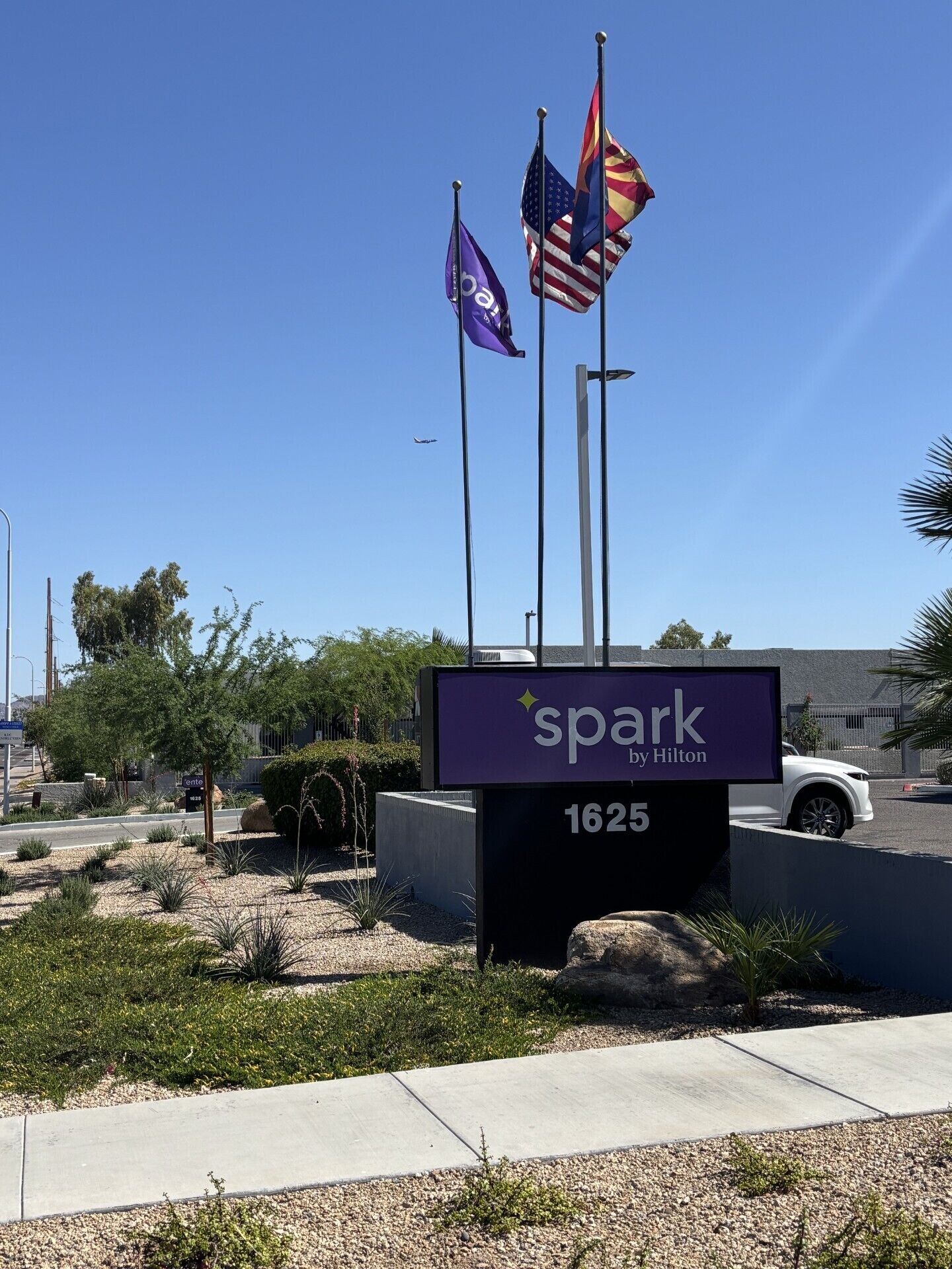 A hotel sign with flags, a parking lot, and a clear sky.