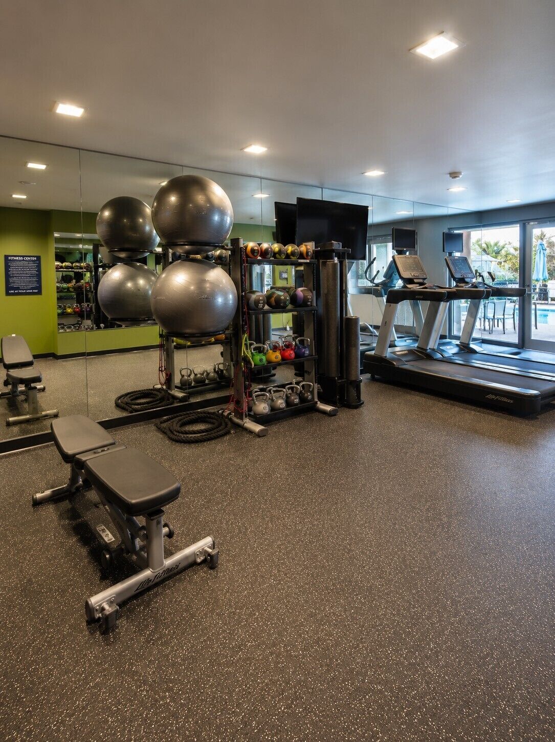 A gym with exercise equipment, treadmills, and a bench.
