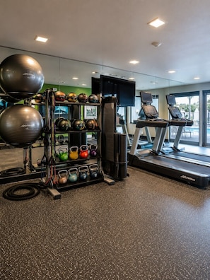 A gym with exercise equipment, treadmills, and a weightlifting area.