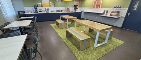 A modern dining area with tables and benches, a counter with various items, and artwork on the walls.