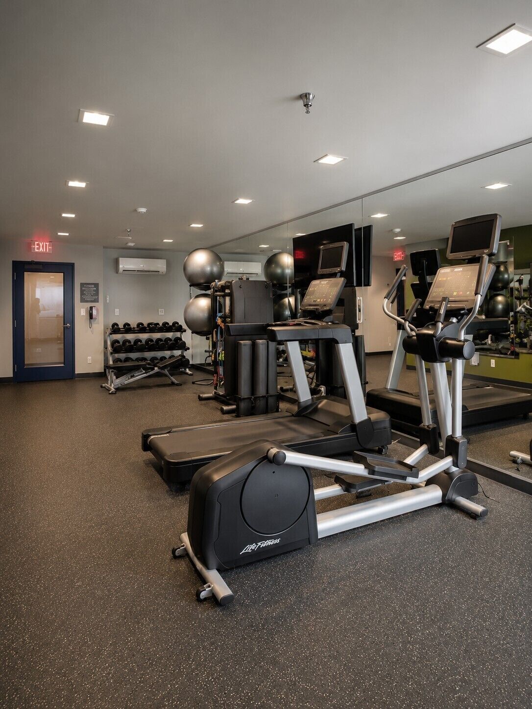 A gym with treadmills, exercise balls, and dumbbells.