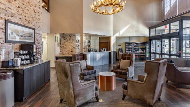 A lobby with a brick wall, a chandelier, a reception desk, and seating area. - Comfort Inn St. Robert / Fort Leonard Wood (St. Robert)