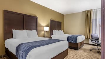 A hotel room with two beds, a nightstand with a lamp, a chair, and a view of the outside through a window with curtains.