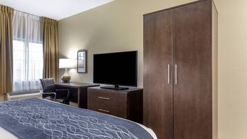 Una habitación de hotel con cama, escritorio con televisor, armario y silla.