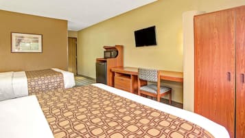 A hotel room with two beds, a desk, a chair, a television, and a wardrobe.