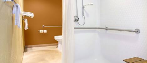 A bathroom with a shower, toilet, and a wooden bench.