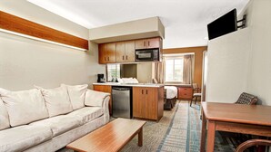 A compact living space with a kitchenette, a sofa, a coffee table, and a dining area. - Microtel Inn & Suites by Wyndham Mason/Kings Island (Mason)