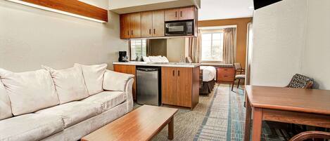 A compact living space with a kitchenette, a sofa, a coffee table, and a dining area.