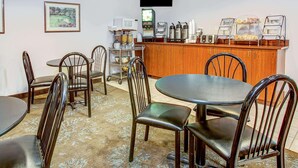 A dining area with wooden tables and chairs, a coffee station, and a microwave. - Microtel Inn & Suites by Wyndham Mason/Kings Island (Mason)
