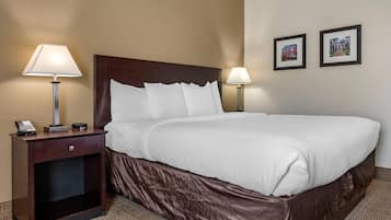 A hotel room with a large bed, two bedside lamps, a nightstand with a phone, and two framed pictures on the wall.