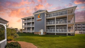 A multi-story hotel with a 'Comfort Suites' sign, featuring balconies and a well-maintained lawn.
