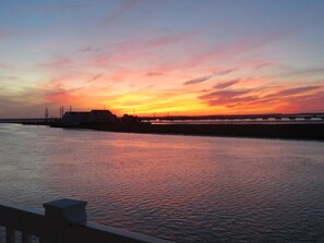 Un atardecer sobre aguas tranquilas con un muelle que se adentra en el agua.