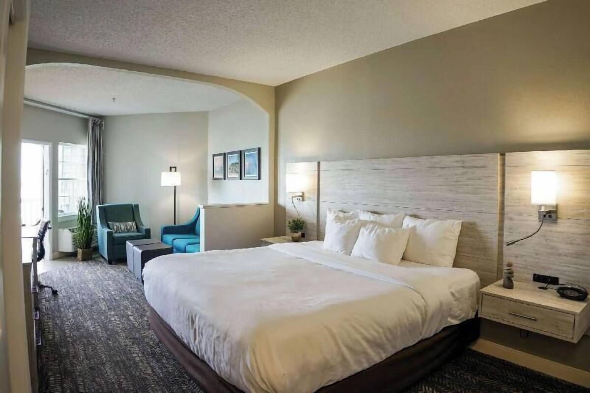 A hotel room with a large bed, bedside tables, a desk, and a chair.