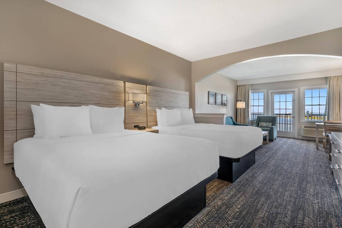 A hotel room with two beds, a desk, and a chair.