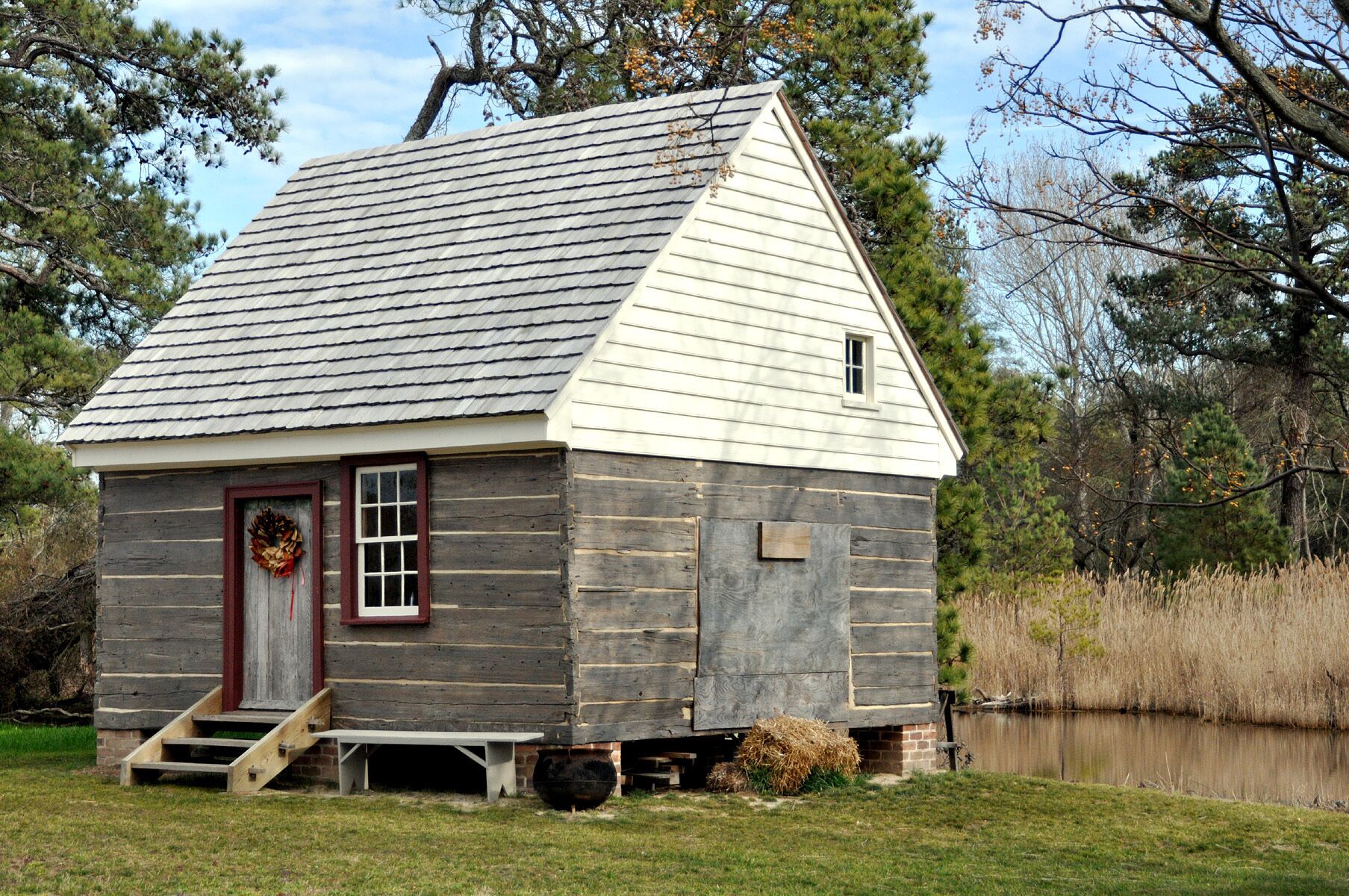 A small wooden cabin with a steep gabled roof, a front door with a wreath, and a small window.