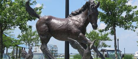 Une statue de cheval en bronze, dans un parc avec des arbres et un lampadaire.