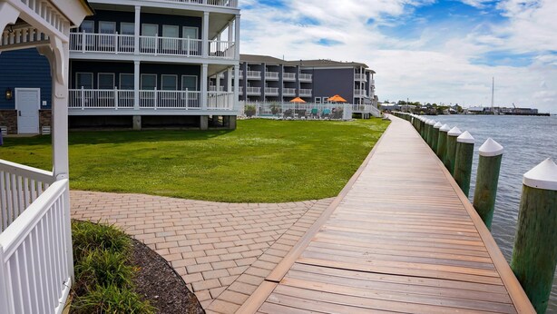 A waterfront hotel with a wooden deck, grassy lawn, and multiple balconies.