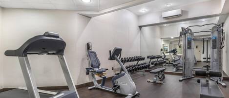 A gym with a treadmill, elliptical, and weight machines.