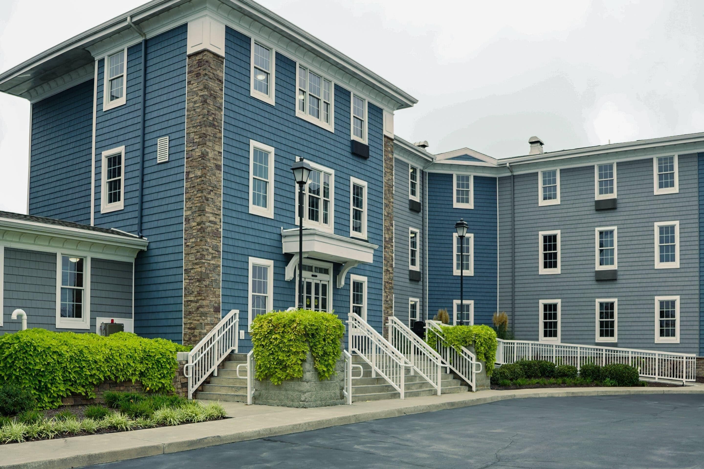 A multi-story residential building with a blue exterior, white trim, and stone accents.