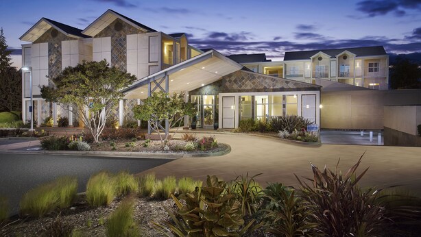 A modern hotel with a spacious entrance, a covered outdoor area, and a landscaped garden. - Corporate Inn Sunnyvale (Sunnyvale)