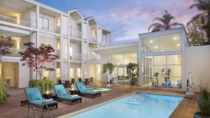 A modern hotel with a pool area, lounge chairs, and a well-lit interior. - Corporate Inn Sunnyvale (Sunnyvale)
