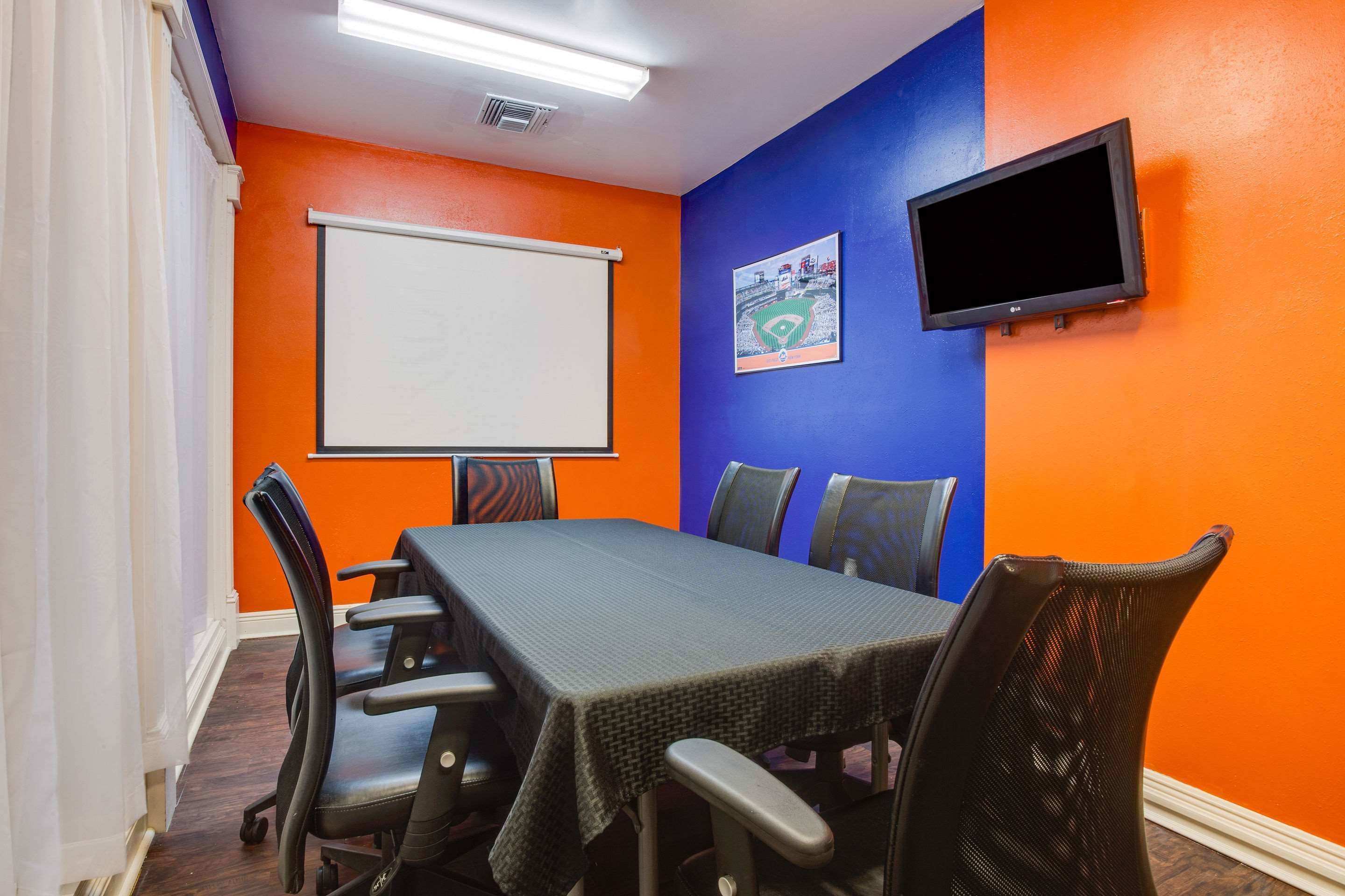 A conference room with a whiteboard, a flat-screen TV, and a table with chairs.