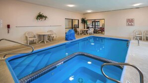 Una piscina con borda piastrellata in blu, circondata da sedie bianche e un tavolo coperto.