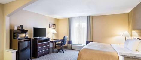 Une chambre d’hôtel équipée d’un lit, d’un bureau, d’une chaise, d’une télévision, d’un four à micro-ondes et de la climatisation.