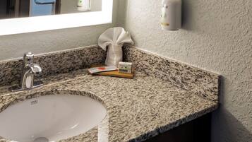 A bathroom with a granite countertop, a white sink, and a window.