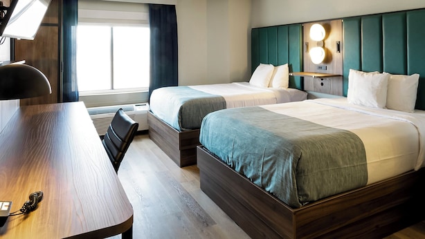 A hotel room with two beds, a desk, and a window with curtains. - Wingate by Wyndham Owensboro (Owensboro)